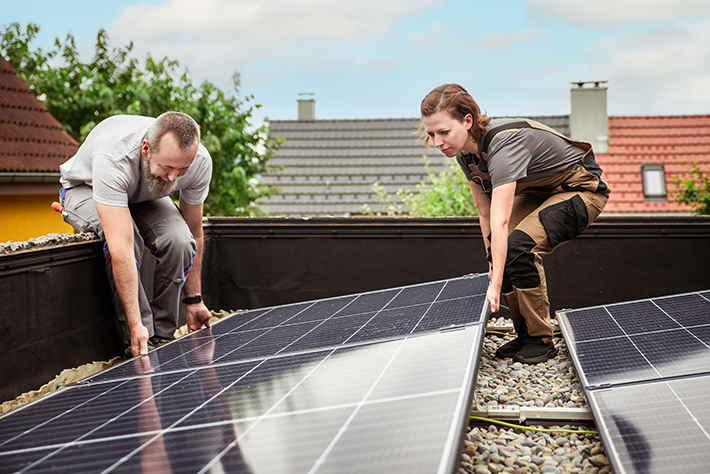 Male and female electricians installing solar modules on roof © Adobe Stock/M.Dörr & M.Frommherz
